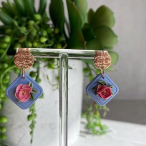 pink floral earrings on blue background