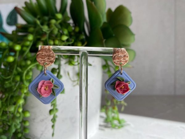 pink floral earrings on blue background