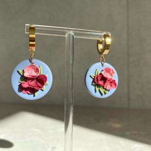floral earrings on circular blue background