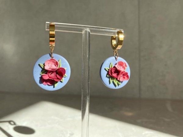 floral earrings on circular blue background